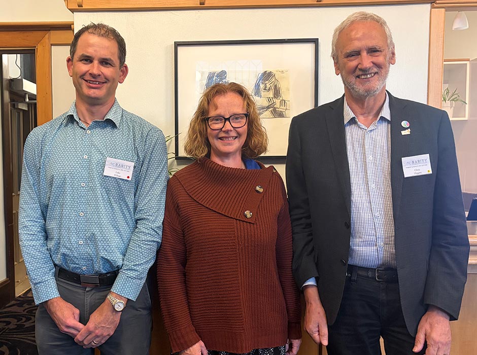 Two men and a woman at a symposium posing for a photo
