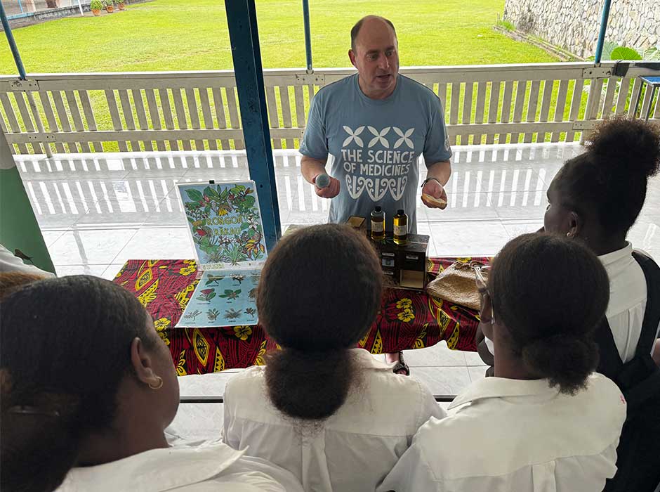 A man stands at the front of a classroom chatting to young adults