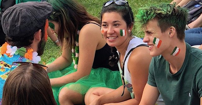 Students with irish flags facepaint sitting on the lawn and chatting