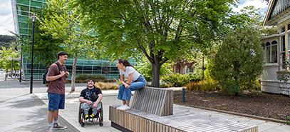 Three Māori students talking outside the Māori Centre and CFI by park bench image