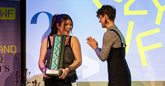 A woman receiving a trophy from another woman