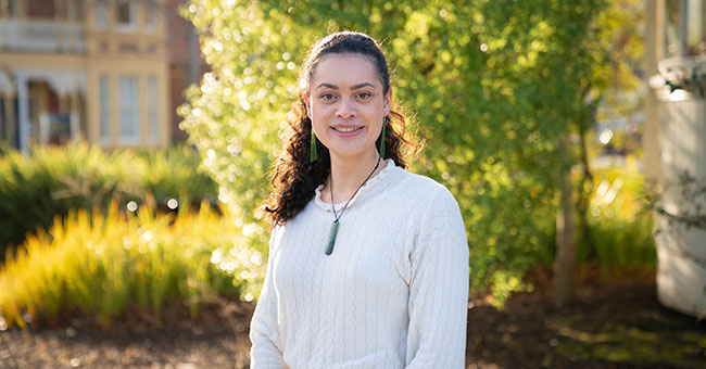 Young Māori woman standing with trees in the background
