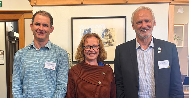 Two men and a woman at a symposium posing for a photo
