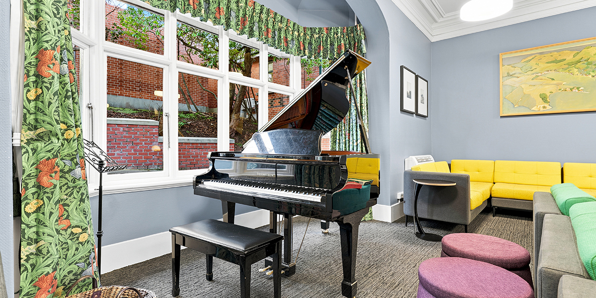 Common area with piano by large window and sofas