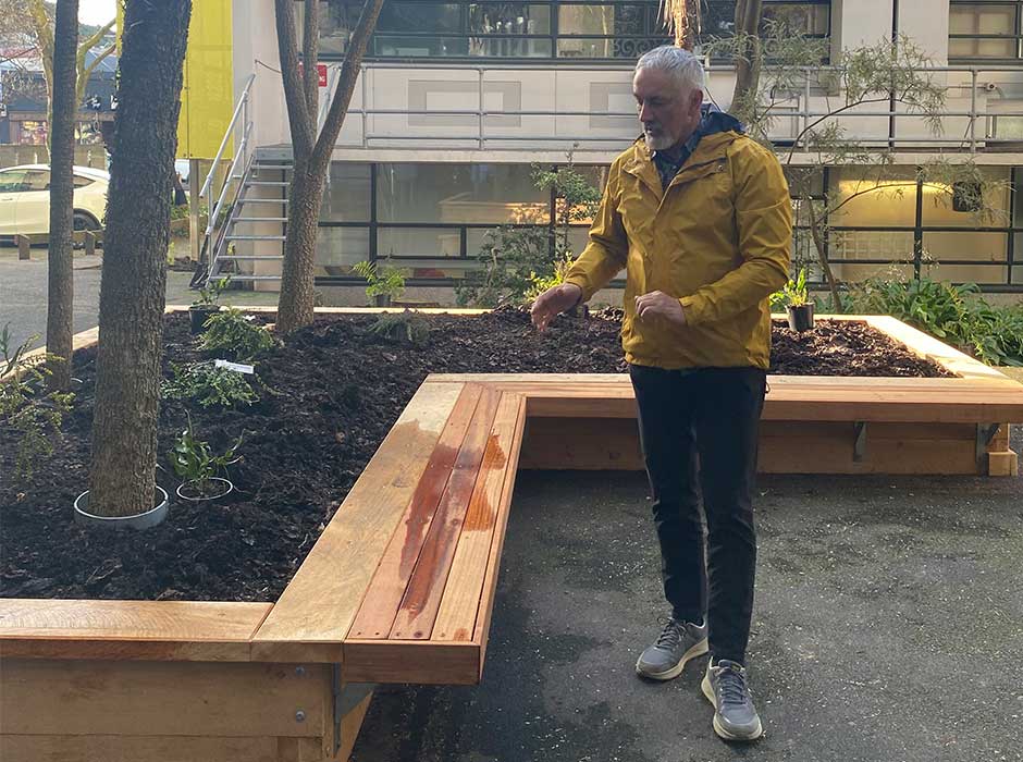 A person standing next to the raised bed, speaking to other people