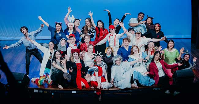 a group of people gathered on a stage in various costumes to promote their upcoming show