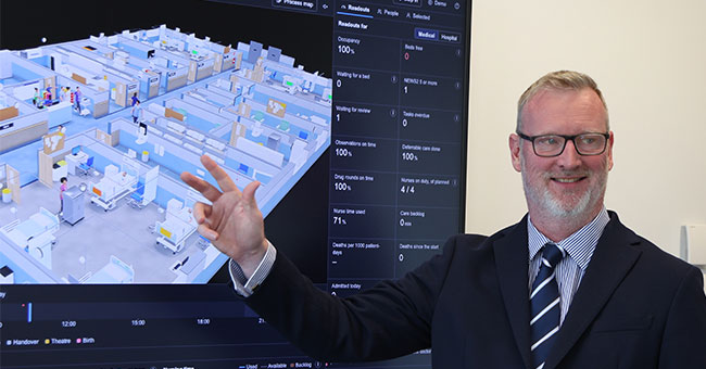 Associate Professor Chris Paton pictured in front of a prototype for a 3D agent-based hospital simulator.