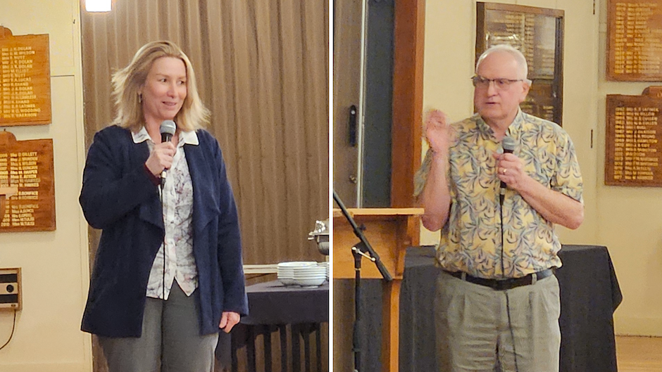 A woman and a man stand and talk using microphones.