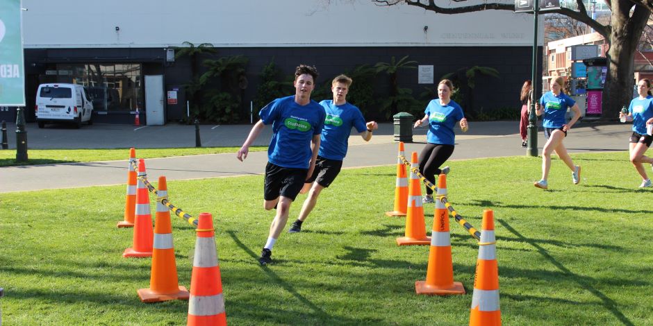 A group of students participating in the Amazing Race event, running through cones on the Otago Museum reserve