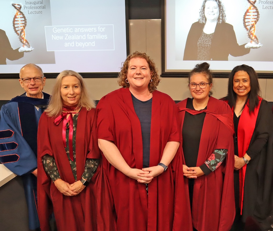 Five people dressed in academic regalia smile at the camera.