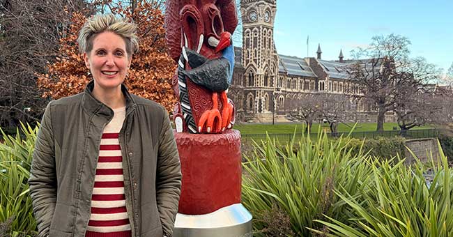 a woman standing in front of the pou by Water of Leith in front of the clocktower