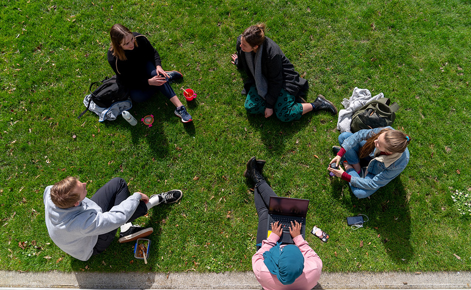 A birds eye view of students sitting in a circle on tht lawn,