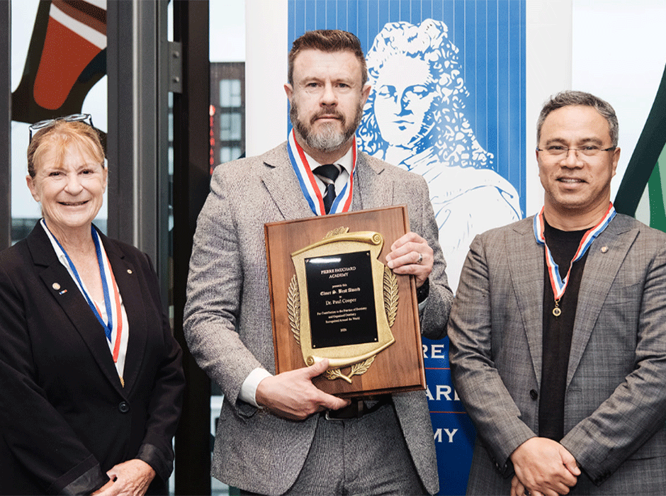man holding award, with woman and man either side