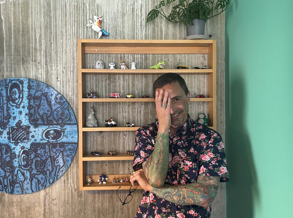 A man covering half his face with his hand, standing in front of a wall display