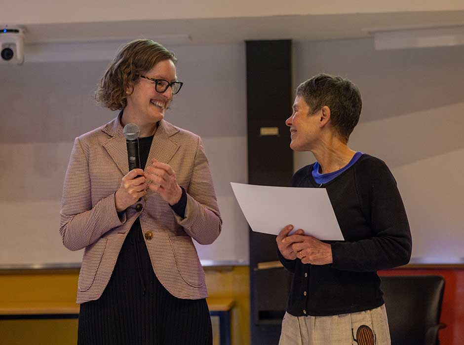 Two women stand next to each other, smiling, one holding a certificate