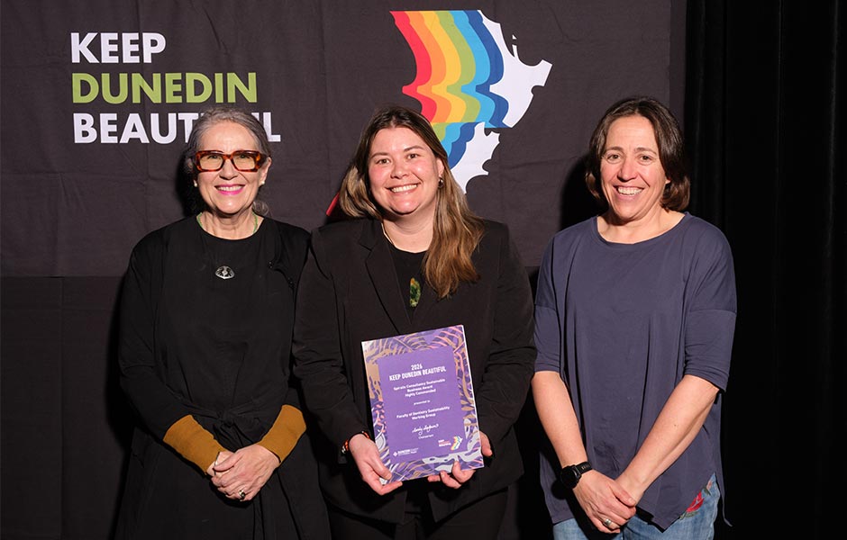 Three women pose with an award in front of the Keep Dunedin Beautiful logo.