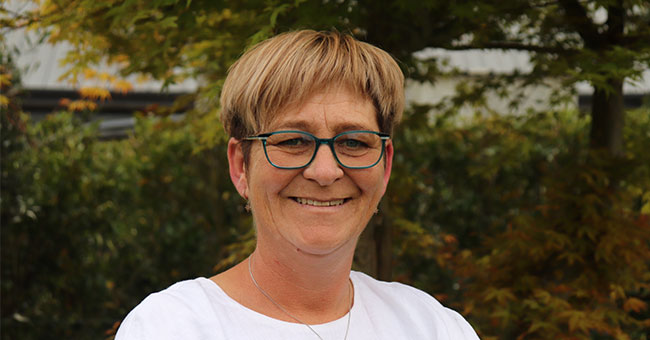 A photo of a woman in glasses pictured outside.