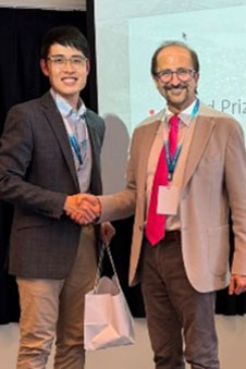 Two men shake hands over an award.