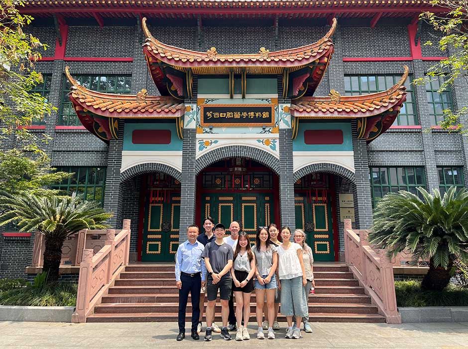 A row of people stand in front of a large traditional style building in China