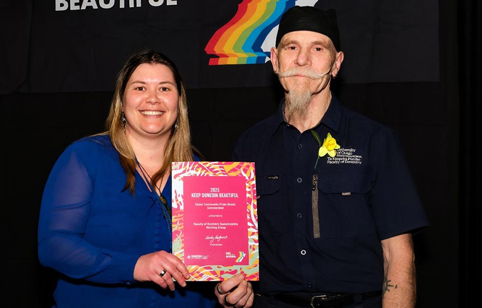 Two people pose with an award.
