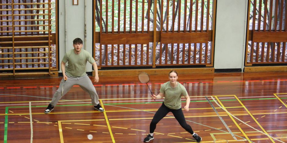 A view from above of two students focusing on a shuttlecock during a game of badminton