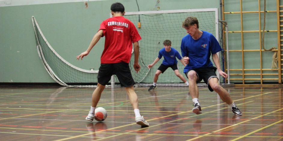 Three futsal players near a goal