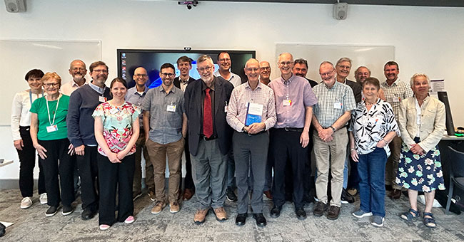 A group of people pose with a man holding a Festschrift.