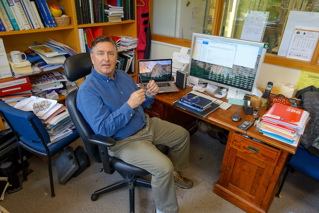 Krause surrounded by books and computer monitors in his office at the University of Otago