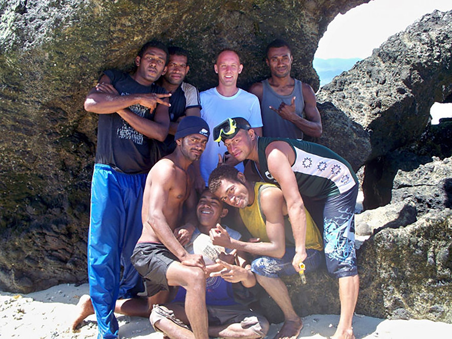 John Shaver at the beach surrounded by a group of young Fijian men