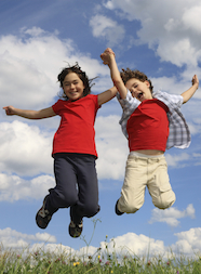 two children jumping in a field