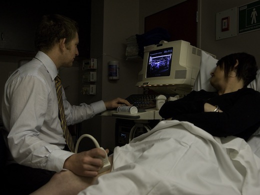 Male sonographer performing ultrasound scan of leg