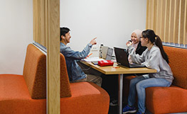 Three students studying in orange booth