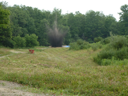 Using PETM/TNT charges to create some man-made maars, in Buffalo, NY. Boomb, a several metre high column of dirt emanates from a man made explosion in the ground.