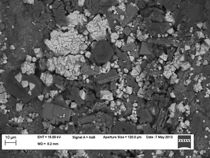 SEM image of the surface of an arsenic-rich (>24,000 ppm) ore sample which has undergone 6 months of kinetic leaching experiments. The image shows significant precipitation of secondary sulphates (grey) and As-bearing minerals (white). 