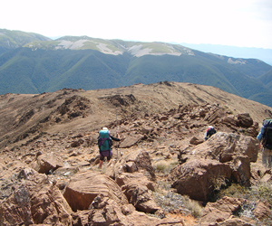 Geologists hiking down the barren and rugged ridge to Hunters Hut, Red Hills, Nelson
