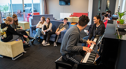 Students playing on a piano in a common area