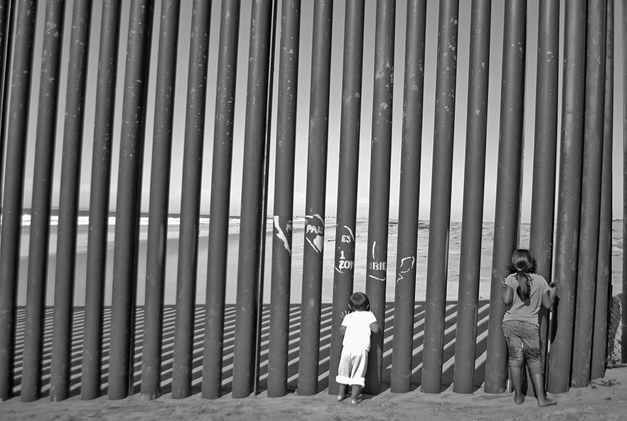 Children gazing through a border wall image