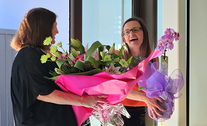 Professor Rich recieving flowers from Client Service Adminstrator Cate Lippers and Head of Department Professor Julia Horsfield banner