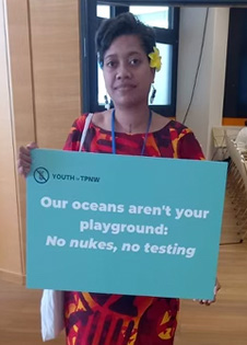 Mere Tuilau holding a Youth for Treaty on the Prohibition of Nuclear Weapons sign which reads, “Our oceans aren't your playground: No nukes, no testing”.