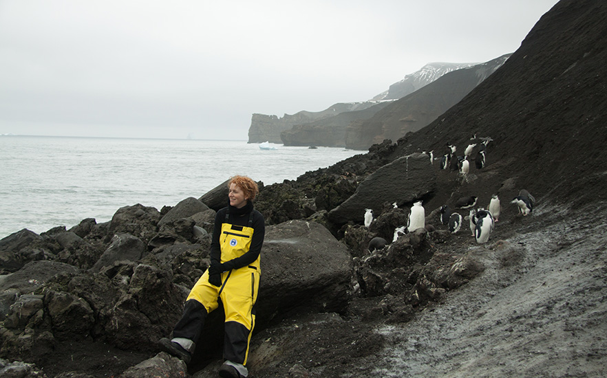 Associate Professor Ceridwen Fraser overlooking the ocean with penguins behind her image