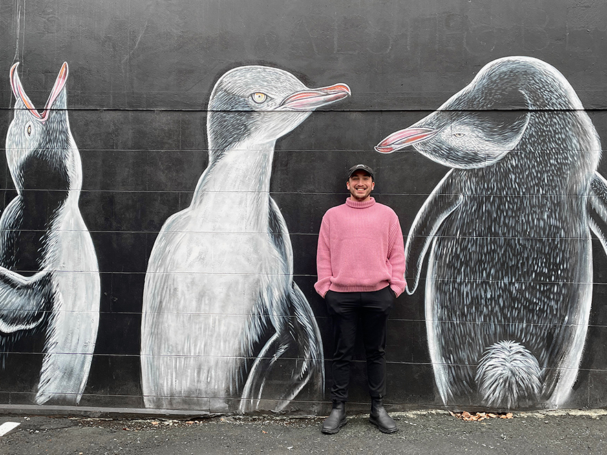 Thor Elley stands in front of penguin mural