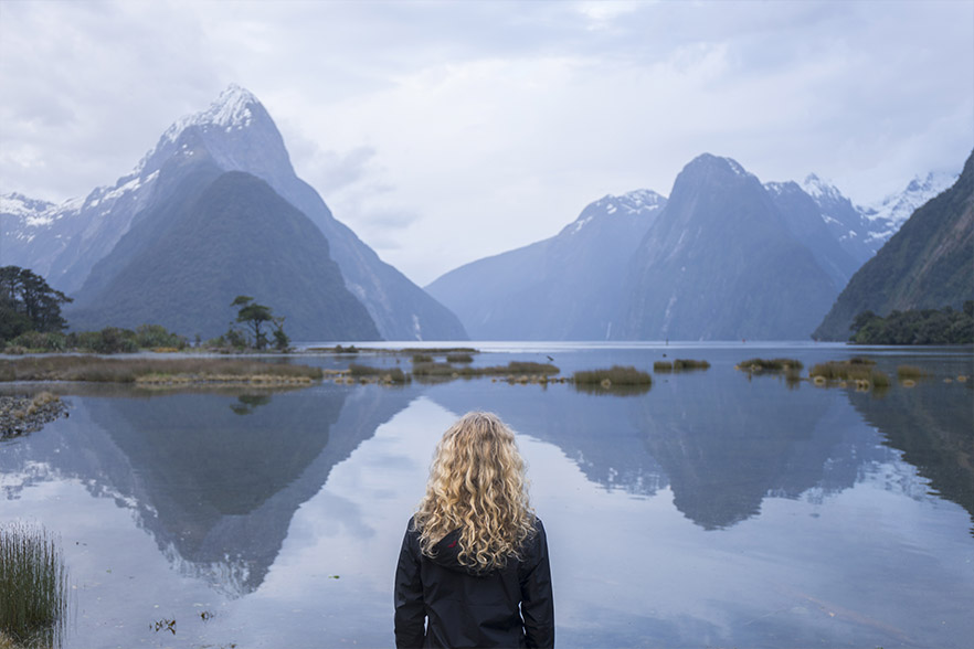 Woman looking at the mountains around Milford Sound