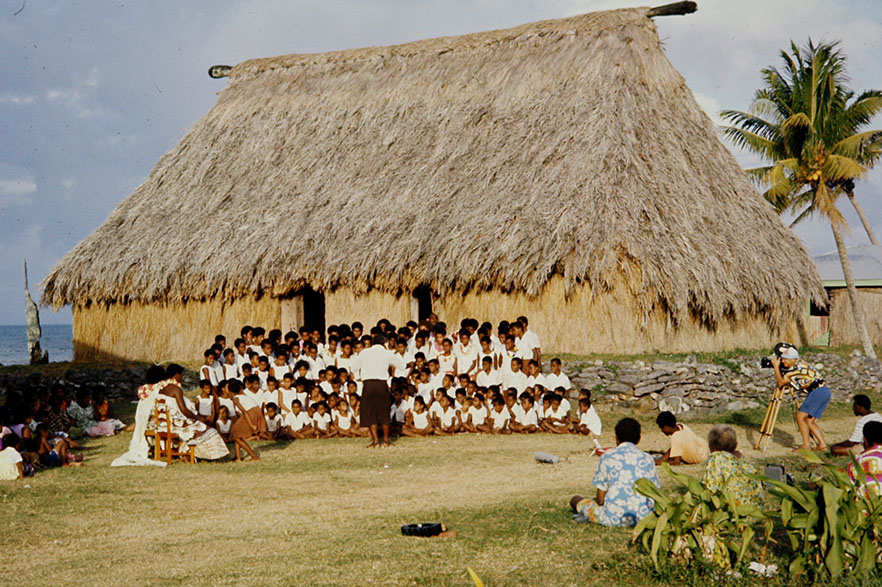 Historic photo of a group of people outside of a traditional building in Fiji