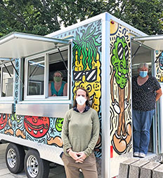 Three people standing around a food truck
