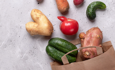 Odd-shaped vegetables spilling out of a paper bag