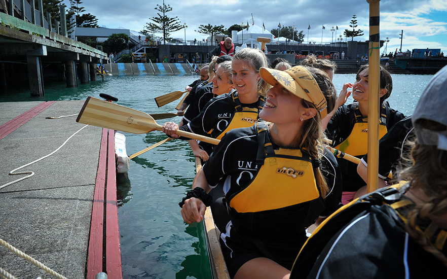 Girls in a dragon boat by the wharf in Wellington image