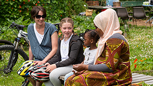 Two mothers sit with their children at a community garden