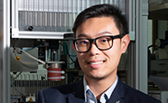 Dr Khoon Lim with 3D printer behind 186 thumb