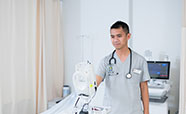 Nursing student standing by bed with equipment