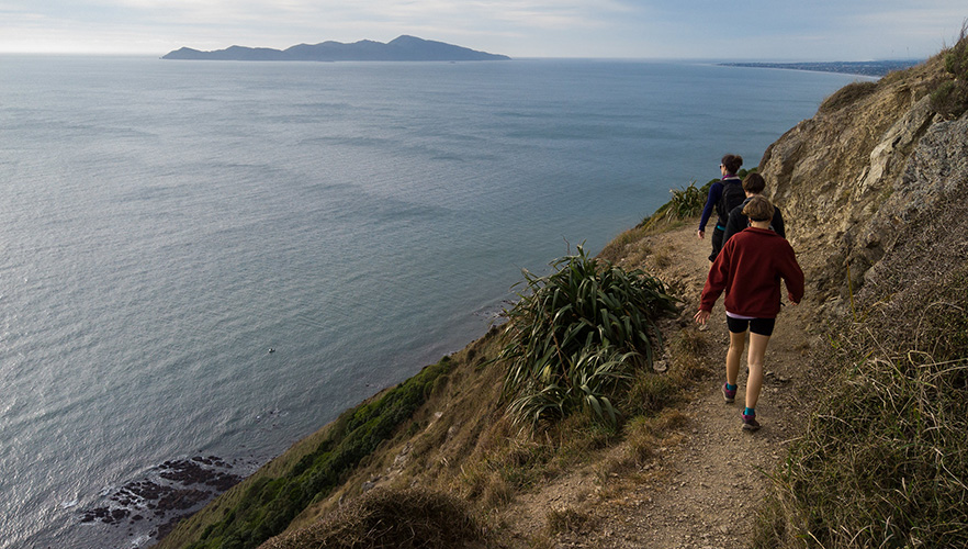 Three people walking the Escarpment walk with the ocean to the left of them image